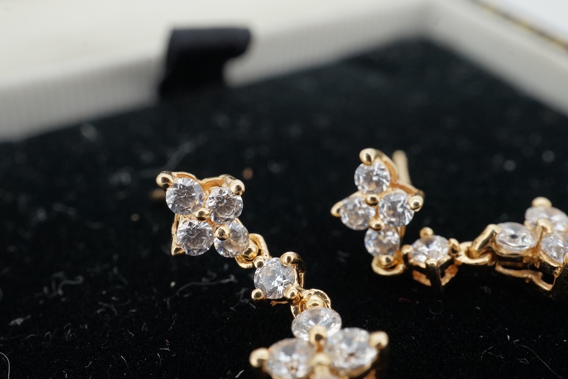 A modern yellow metal (stamped 585) and cubic zirconia set line bracelet, 18cm and a pair of similar drop earrings, together with a similar 9k and cubic zirconia set cluster ring, size N.
